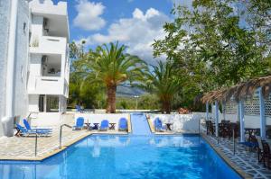 a swimming pool with blue chairs and palm trees at Castello in Limenaria