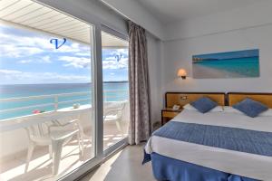 een slaapkamer met een bed en een balkon met uitzicht op de oceaan bij Hotel Voramar in Cala Millor