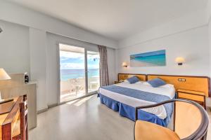 a hotel room with a bed and a view of the ocean at Hotel Voramar in Cala Millor