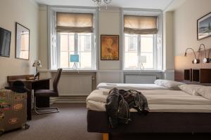 1 dormitorio con 2 camas, escritorio y 2 ventanas en Castle House Inn en Estocolmo