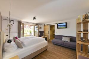 a bedroom with a large white bed and a couch at Pension Waldkristall in Frauenau