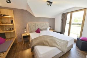 una camera da letto con un grande letto bianco con cuscini viola di Pension Waldkristall a Frauenau