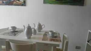 a white table with two vases and cups on it at Appartamenti in Villa Nicanda in Porto Columbu - Perdʼe Sali
