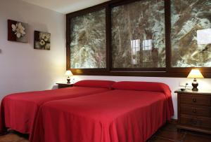 a bedroom with a red bed with a large window at Hostal Palomares in Salobreña