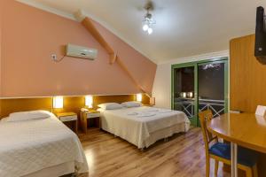 um quarto de hotel com duas camas e uma mesa e uma secretária em Vila Rica Pousada em Nova Petrópolis