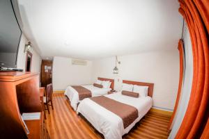 a hotel room with two beds and a flat screen tv at Howard Johnson by Wyndham Morelia Calle Real in Morelia