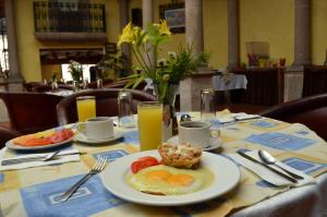 a table with a plate of eggs and fruit on it at Howard Johnson by Wyndham Morelia Calle Real in Morelia