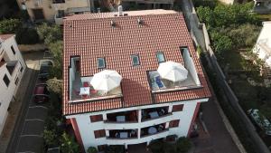 une vue aérienne sur une maison avec deux parasols sur le toit dans l'établissement Apartmani Adrijan Krk, à Krk