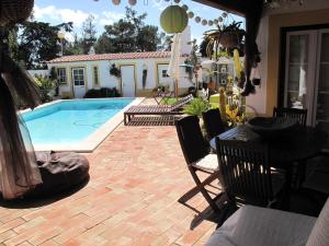 a patio with a pool and a table and chairs at Casa dos Cactos in Vila Nova de Milfontes