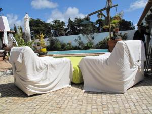 2 sillas cubiertas de sábanas junto a una piscina en Casa dos Cactos, en Vila Nova de Milfontes
