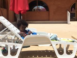 a young child sitting in a lawn chair at Baobab Lodge in Fadial
