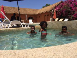 three children are swimming in a swimming pool at Baobab Lodge in Fadial