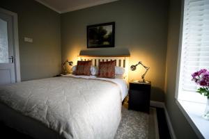 een slaapkamer met een wit bed en een raam bij The Old Cottage in Doolin