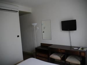 a hotel room with a bed and a desk and a television at Hôtel Le Barry, Toulouse Nord in Gratentour