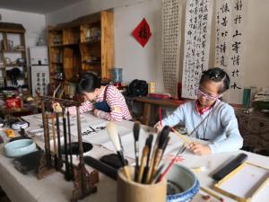 two women working on a table in a room at Zhangjiajie Jijiehao Inn in Zhangjiajie