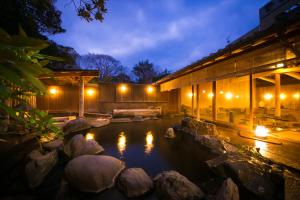 a pond with rocks in front of a building at night at Yakakutei in Kirishima