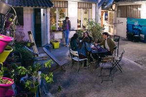 un groupe de personnes assises à une table dans un jardin dans l'établissement Le Flâneur Guesthouse, à Lyon