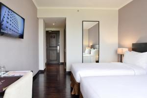 a hotel room with two beds and a tv at Samala Hotel Jakarta Cengkareng in Jakarta