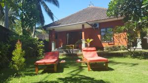 zwei Stühle im Gras vor einem Haus in der Unterkunft Gede's Homestay in Tejakula