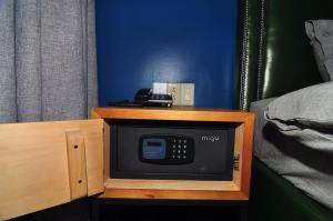 a small microwave in a wooden cabinet next to a bed at Saipan Skyline Designers Hotel in Saipan
