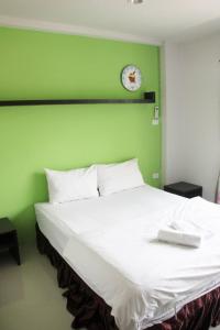 a bed with a green wall with a clock on it at Cozy Rabbit Hotel in Thung Song