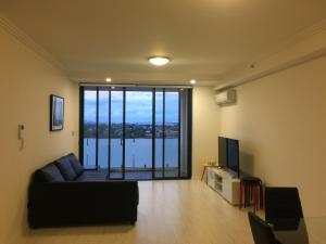 a living room with a couch and a television at Hurstville New apartment with city view in Sydney