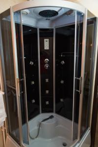 a shower with glass doors in a room at Pensiunea Dallas in Botoşani