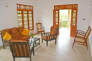 a living room with chairs and a table and doors at Villa Chaya in Hikkaduwa