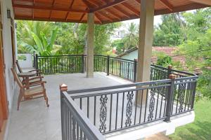 a porch with a railing and a chair on it at Villa Chaya in Hikkaduwa