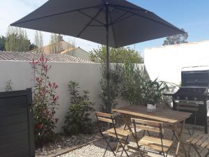 a picnic table with an umbrella next to a grill at La Cabane Manon in La Guérinière