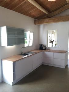 cocina con armarios blancos y techo de madera en Les Genets, en Ker borny