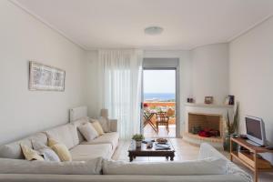 een witte woonkamer met een witte bank en een open haard bij Comfortable house with amazing view in Anavissos