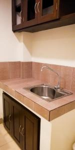 a kitchen with a sink and wooden cabinets at Veranda Residence Inn in Tacloban