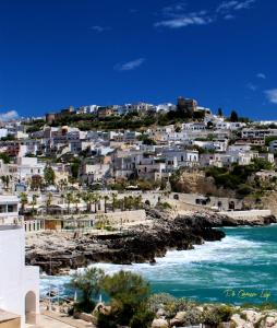 a group of white houses on a hill next to the ocean at Hotel Degli Ulivi in Castro di Lecce