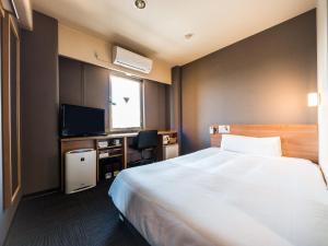 a hotel room with a bed and a desk and a television at Super Hotel Inn Kurashiki Mizushima in Kurashiki