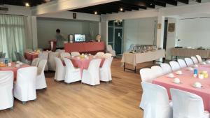 a banquet hall with tables and white chairs and a man at Sinkiat Thani Hotel in Satun