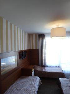 una camera d'albergo con due letti e una televisione di MAX Apartamenty - Pokoje - Domki - Restauracja - Basen a Mielno