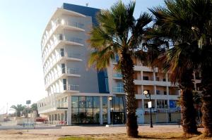 a large building with palm trees in front of it at Water's Edge Hotel in Birżebbuġa
