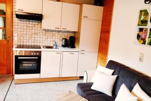 a kitchen with white cabinets and a couch in a room at Ferienwohnungen Wilhelmer in Liesing +14 photos