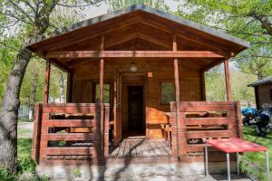Cabaña de madera pequeña con mesa y sillas rojas en Camping Noguera Pallaresa en Sort