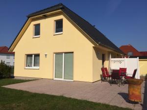 a yellow house with red chairs on a patio at Ferienhaus Arielle in Glowe