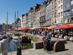 un gruppo di persone sedute su una sporgenza accanto a un fiume di La Petite Parenthèse a Honfleur