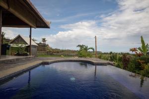 una piscina en un patio con una casa en Medewi Snaffl Beach Villa, en Pulukan