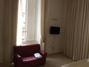 ナポリにあるB&B LA CONIGLIERAの窓付きの客室内の赤い椅子