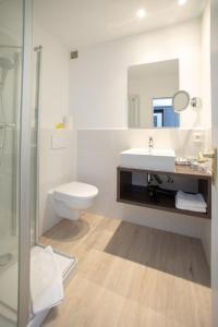 a white bathroom with a sink and a toilet at Hotel Twilling in Sankt Peter-Ording