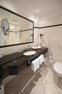 ein Badezimmer mit einem Waschbecken, einem WC und einem Spiegel in der Unterkunft Hotel Twilling in Sankt Peter-Ording