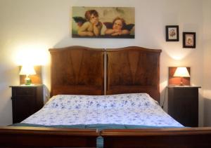1 dormitorio con 1 cama de madera con 2 lámparas y 1 pintura en Casa Portone Paola, en Campiglia dʼOrcia