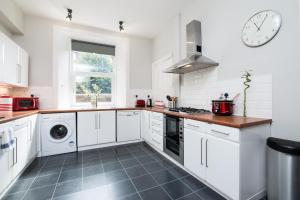 a white kitchen with a sink and a stove at Beautiful, Traditional 2 Bedroom Main Door Flat in Edinburgh