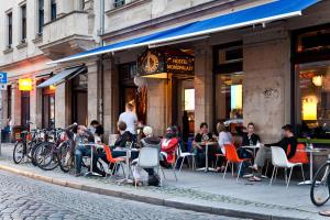 a group of people sitting at tables outside a restaurant at Hostel Mondpalast in Dresden