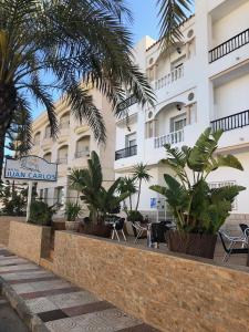 a hotel with palm trees in front of a building at Hostal Juan Carlos in Carboneras